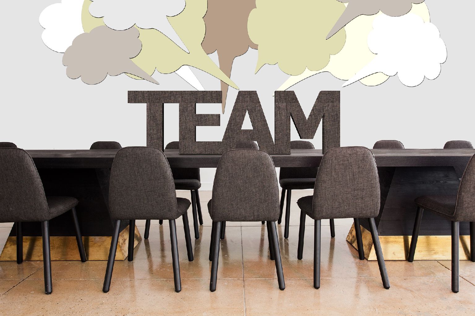 Stühle am Tisch mit dem Wort "TEAM" im Hintergrund.